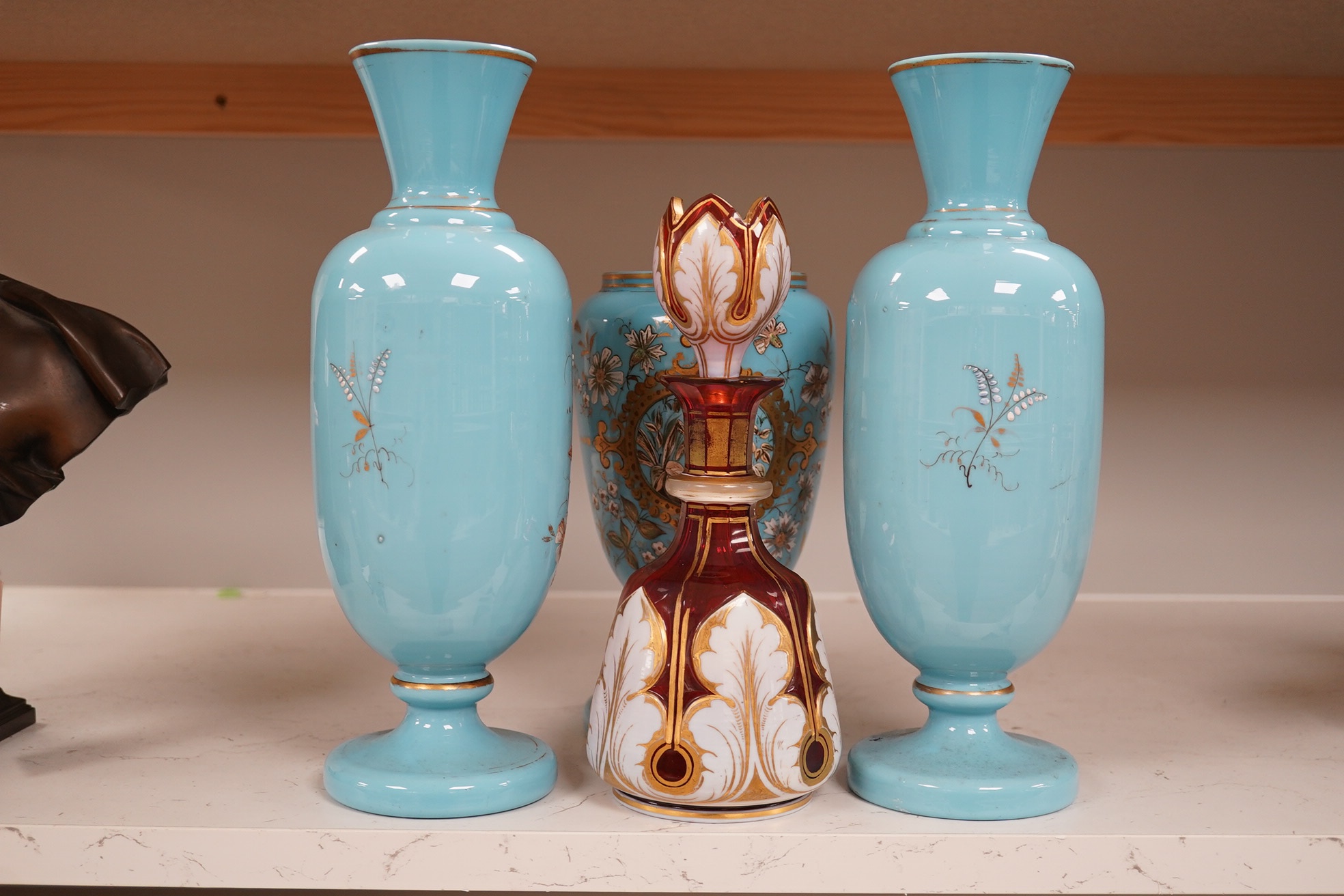 An enamelled glass garniture decorated with Egyptian scenes and a cranberry decanter, largest 29cm high. Condition - poor to fair